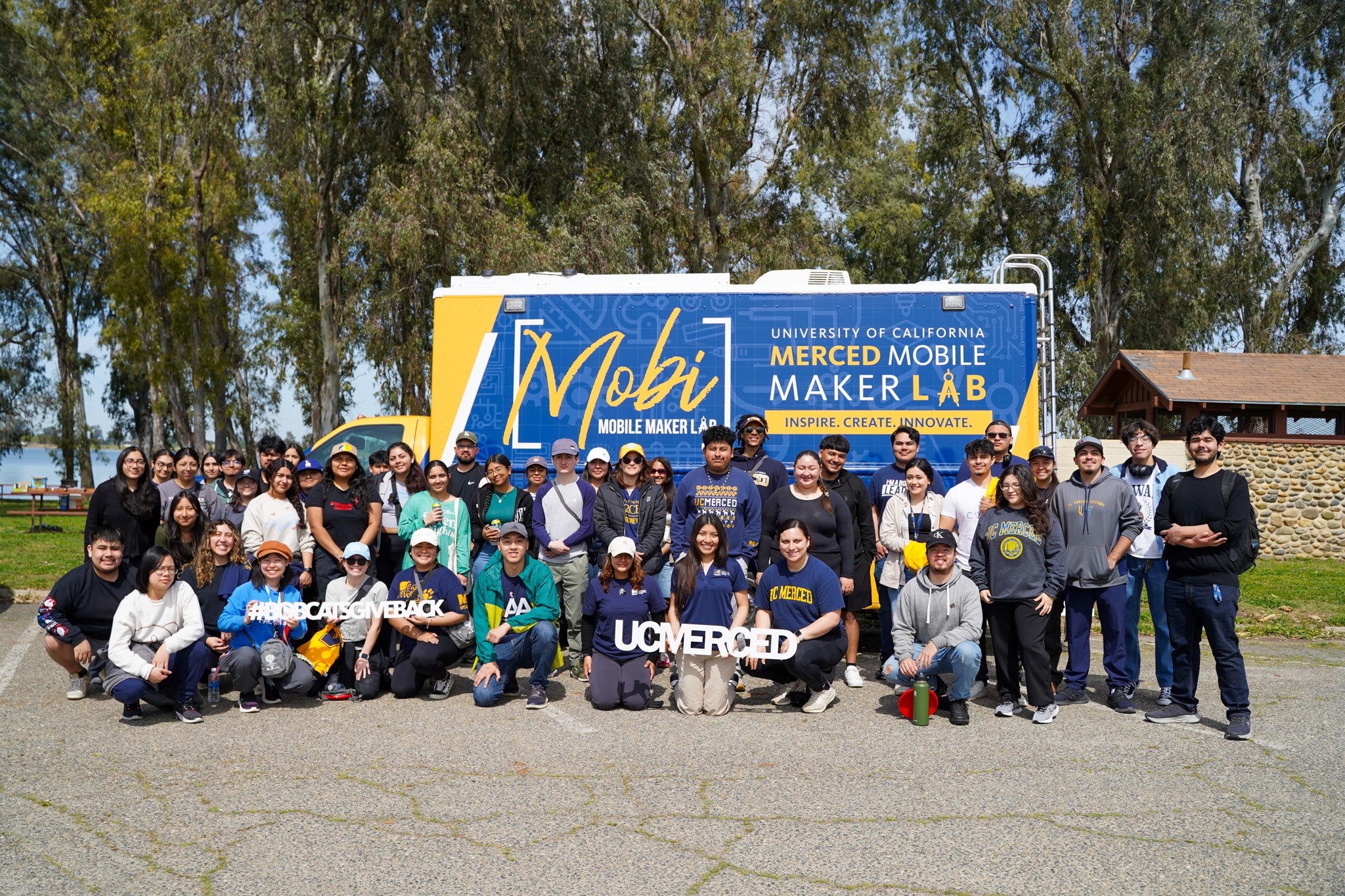 Students and alumni pictured in front of Mobi the Mobile Maker Lab vehicle following a lake clean-up. 